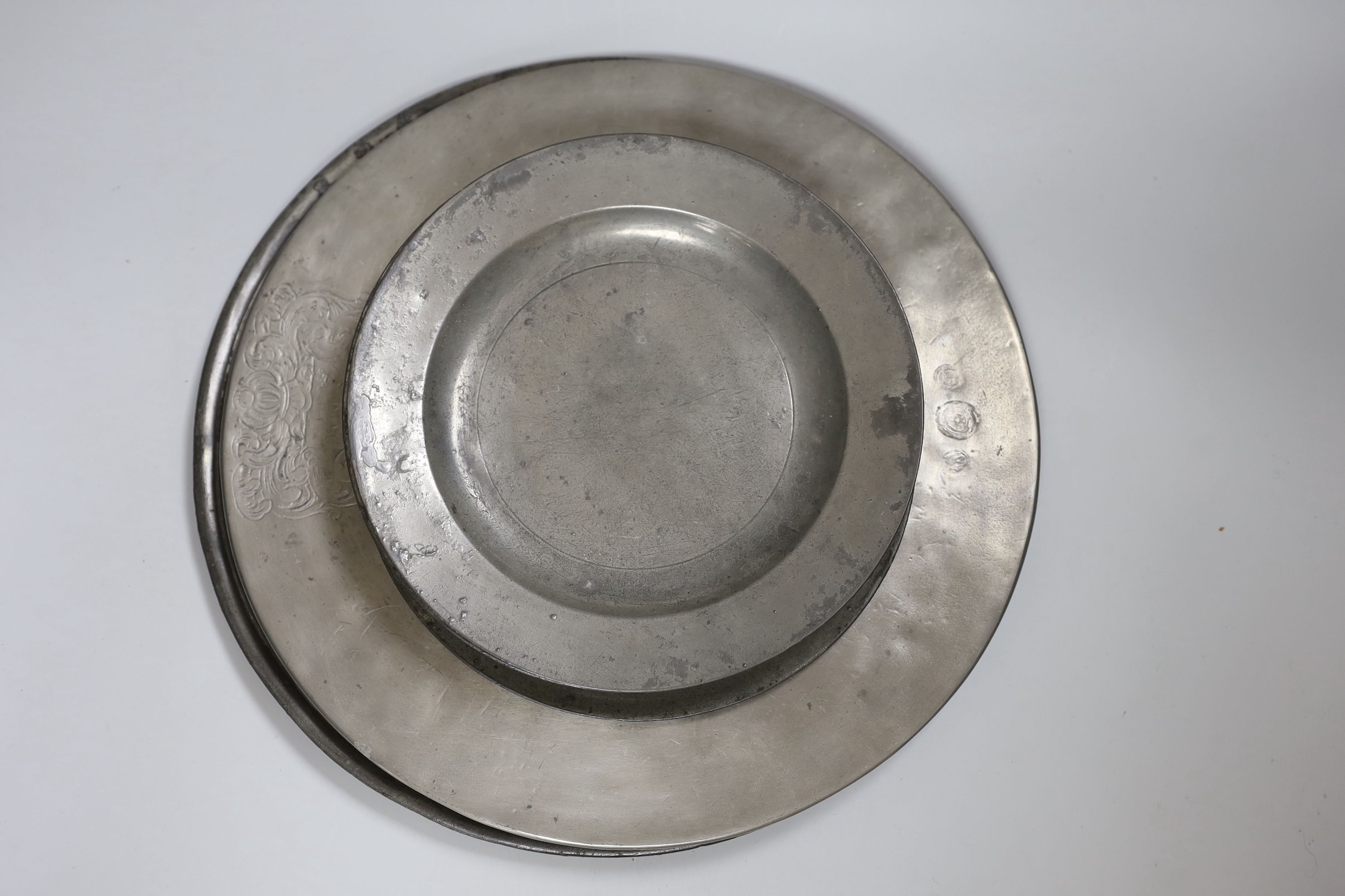 Two pewter chargers one crested, eight plates and a jug, 18th century and later, largest charger 38cms diameter